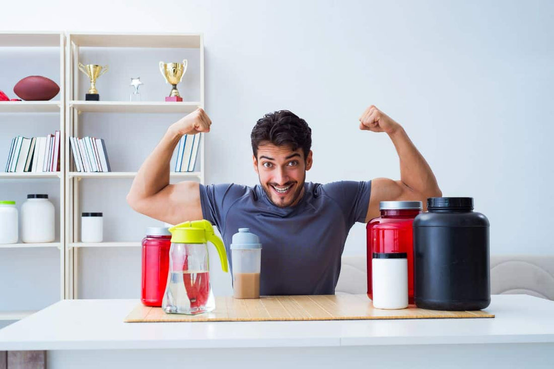 Man flexing at table with muscle building supplements